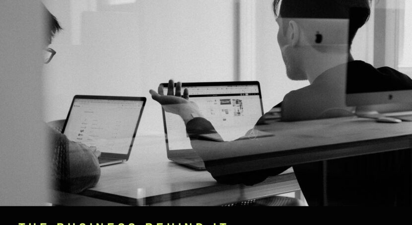 Black and white photo of two people reviewing content on laptops, representing production and shoot turnaround