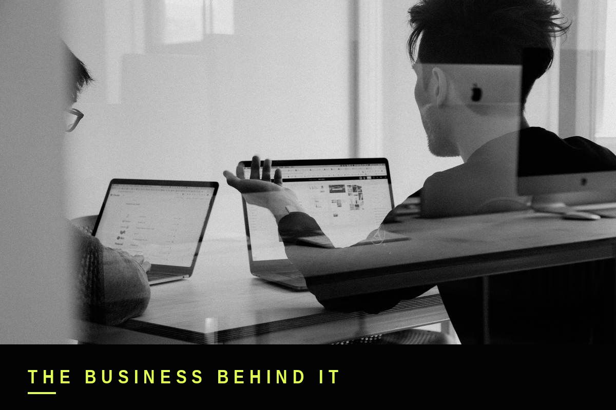 Black and white photo of two people reviewing content on laptops, representing production and shoot turnaround