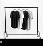 Black and white photograph of a clothing rail holding four t-shirts on hangers in a photography studio