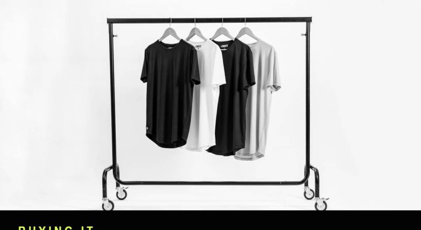 Black and white photograph of a clothing rail holding four t-shirts on hangers in a photography studio