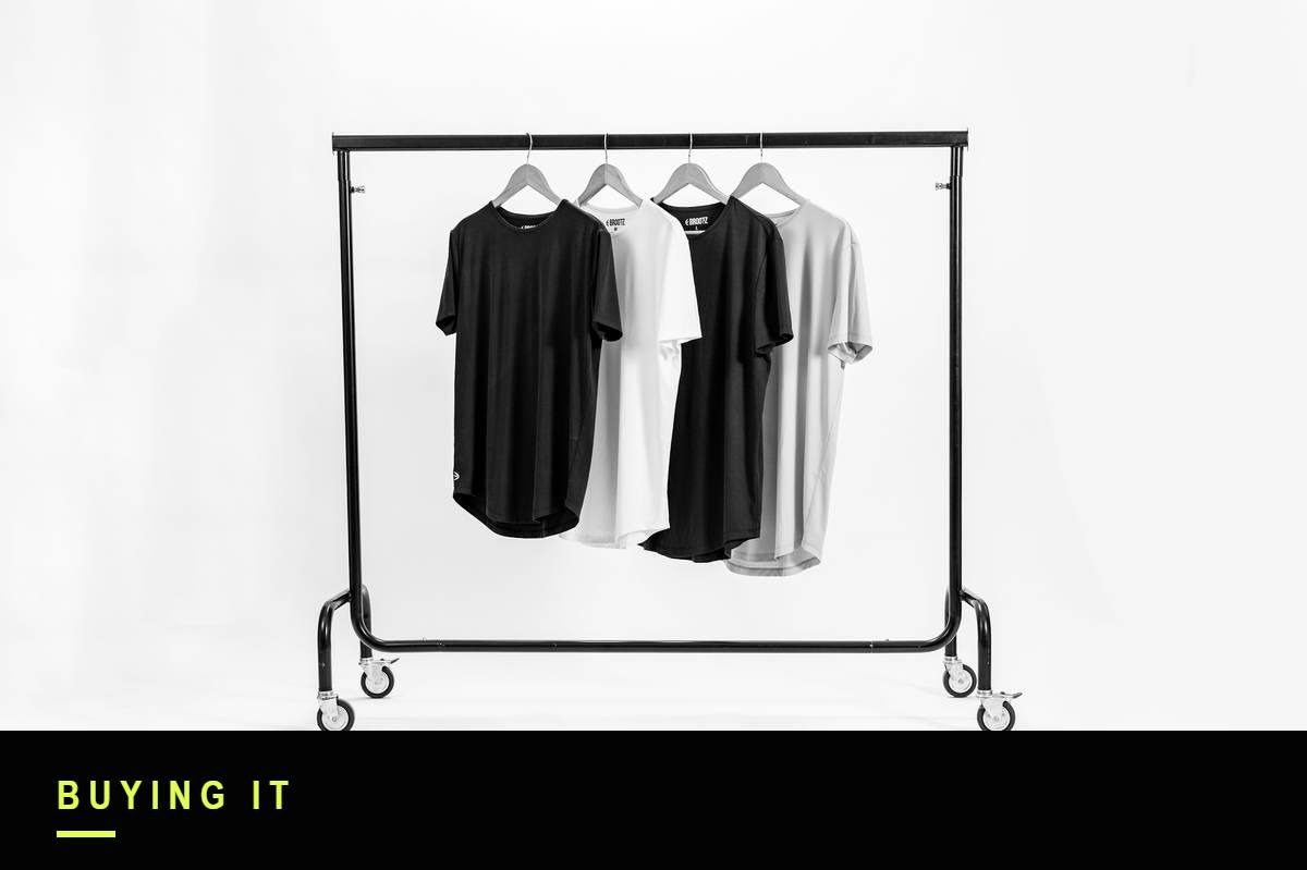 Black and white photograph of a clothing rail holding four t-shirts on hangers in a photography studio